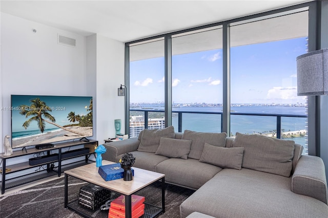 living room featuring a wealth of natural light, a wall of windows, and a water view