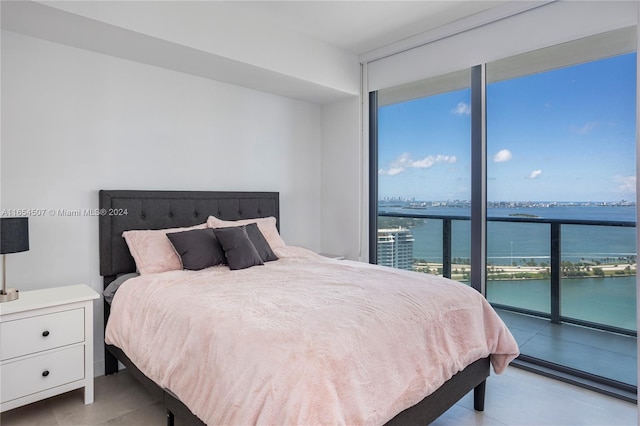 bedroom featuring a water view, expansive windows, and access to exterior