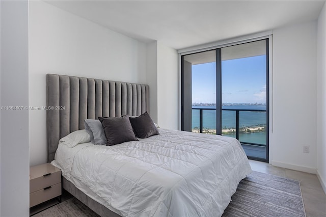 bedroom with floor to ceiling windows, a water view, and access to outside