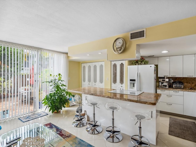 kitchen featuring white cabinetry, white fridge with ice dispenser, and a healthy amount of sunlight