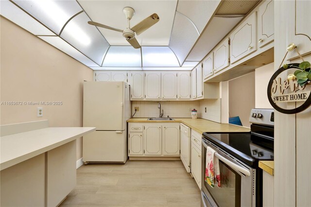 kitchen with light hardwood / wood-style floors, backsplash, white appliances, ceiling fan, and sink