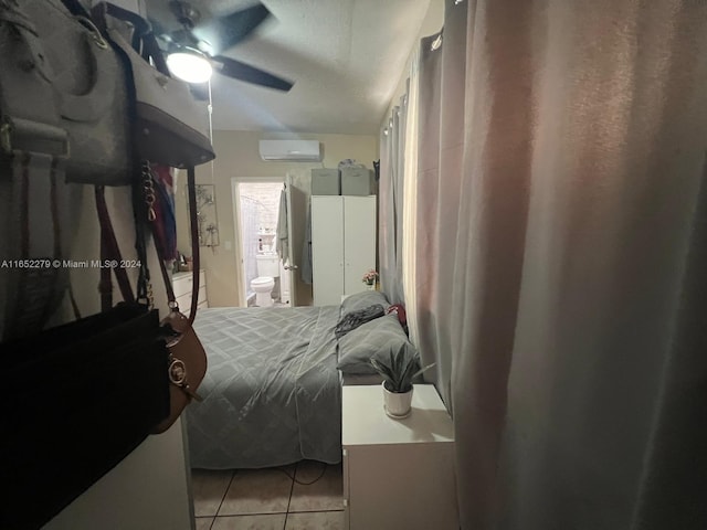 tiled bedroom with connected bathroom, a wall unit AC, and ceiling fan