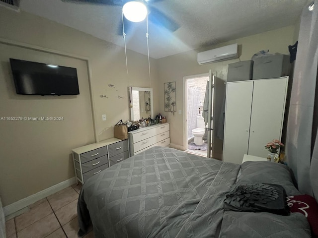 tiled bedroom featuring ceiling fan, connected bathroom, an AC wall unit, and a textured ceiling