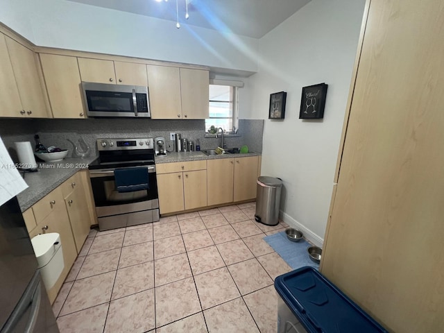 kitchen featuring light brown cabinetry, sink, light tile patterned floors, and appliances with stainless steel finishes