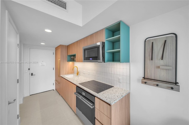 kitchen featuring decorative backsplash, light stone counters, sink, black appliances, and light tile patterned flooring