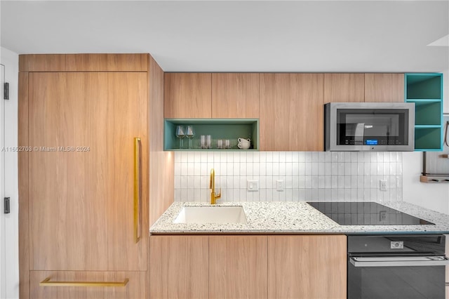 kitchen featuring light stone counters, sink, and black appliances