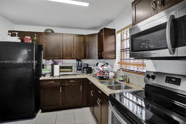 kitchen with sink, light tile patterned floors, appliances with stainless steel finishes, and dark brown cabinets