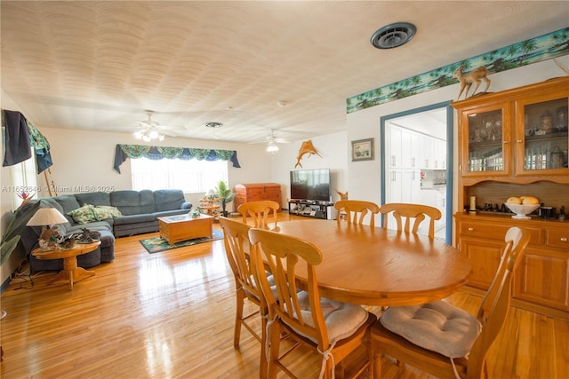 dining space with ceiling fan and light wood-type flooring