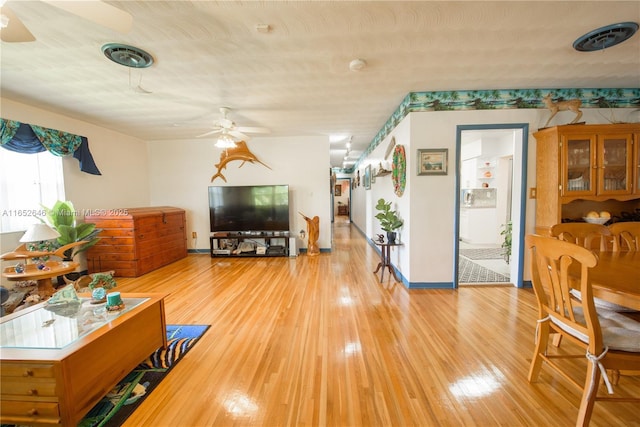 living room featuring ceiling fan, light hardwood / wood-style flooring, and a textured ceiling