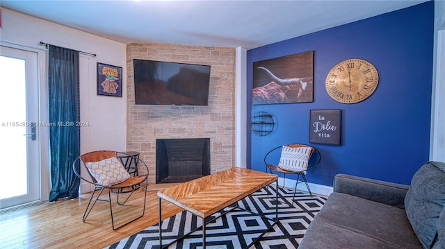 sitting room featuring hardwood / wood-style floors and a stone fireplace