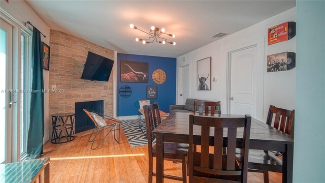 dining area with a fireplace, a notable chandelier, and light hardwood / wood-style flooring