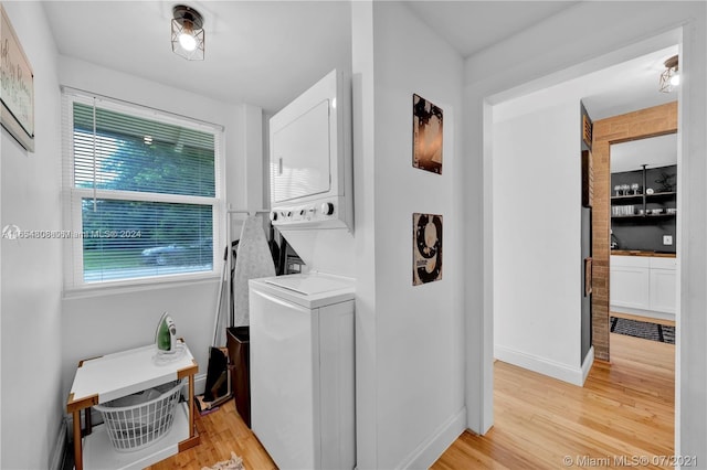 washroom with light wood-type flooring and stacked washing maching and dryer