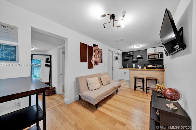 living room with a fireplace, a wall unit AC, sink, and light hardwood / wood-style floors