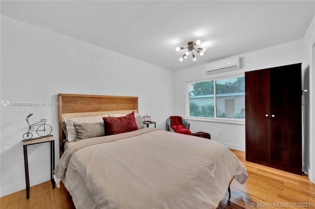 bedroom with a wall mounted air conditioner and light hardwood / wood-style floors