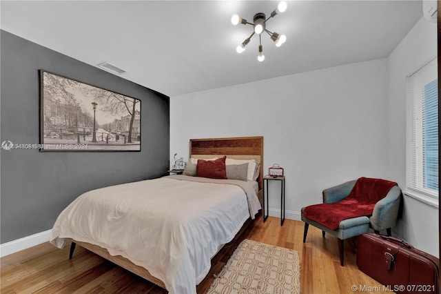 bedroom featuring an inviting chandelier and light hardwood / wood-style floors