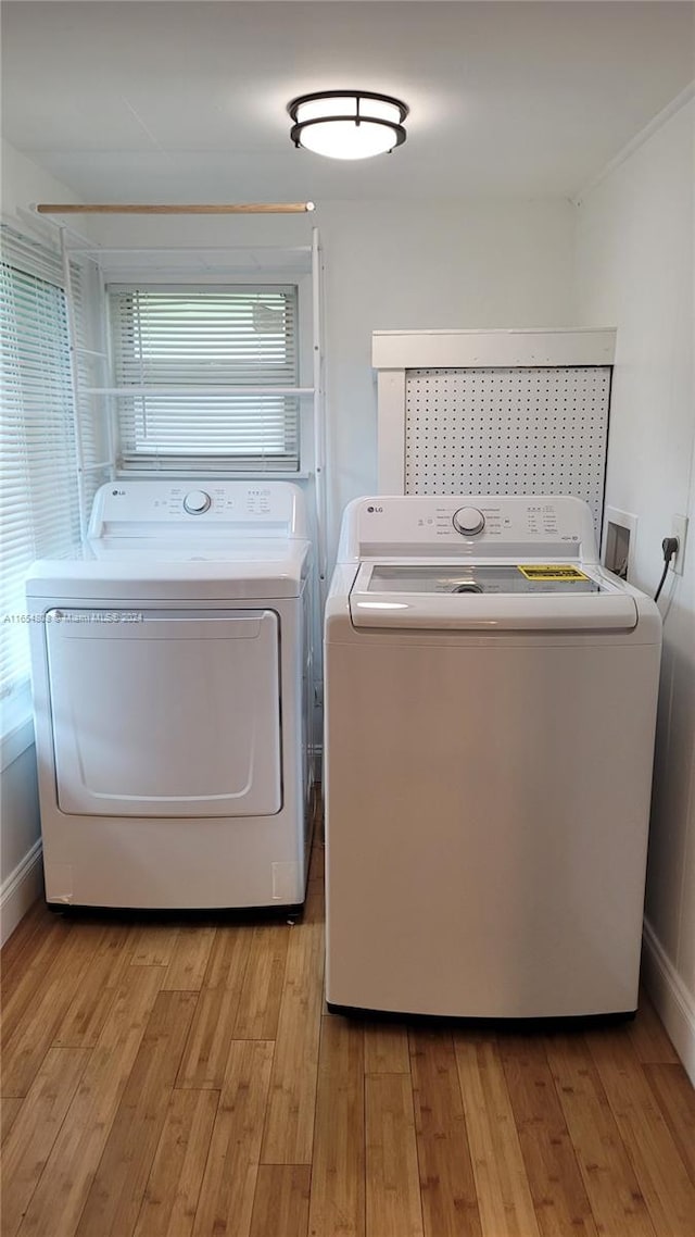 laundry room featuring washing machine and clothes dryer and light hardwood / wood-style flooring