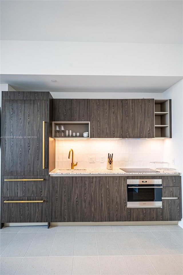 kitchen featuring black cooktop, backsplash, oven, and sink