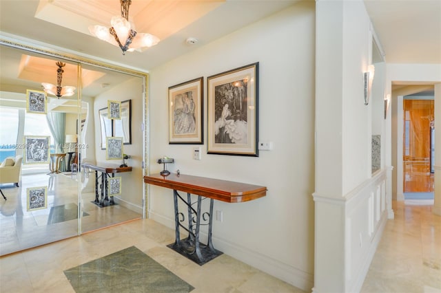 corridor featuring a raised ceiling and an inviting chandelier