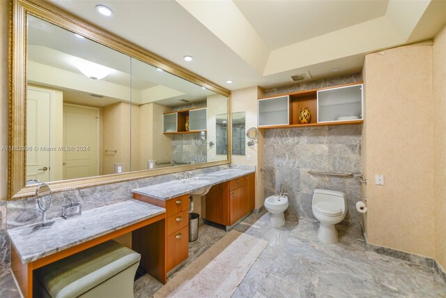 bathroom with toilet, tile walls, a raised ceiling, a bidet, and vanity