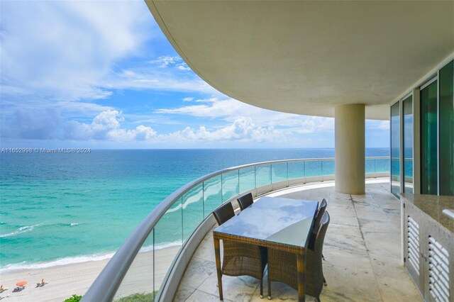 balcony featuring a view of the beach and a water view