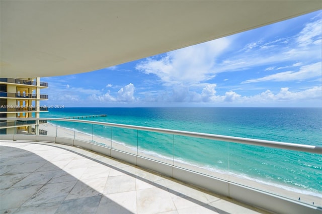 balcony featuring a view of the beach and a water view