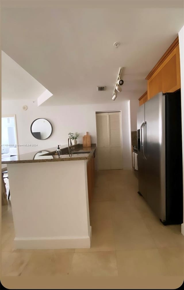 kitchen with sink, rail lighting, light tile patterned floors, and stainless steel refrigerator with ice dispenser