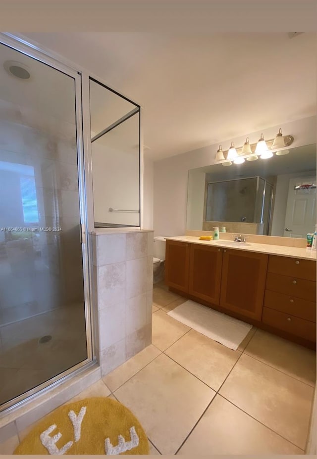 bathroom featuring vanity, toilet, tile patterned floors, and a shower with door