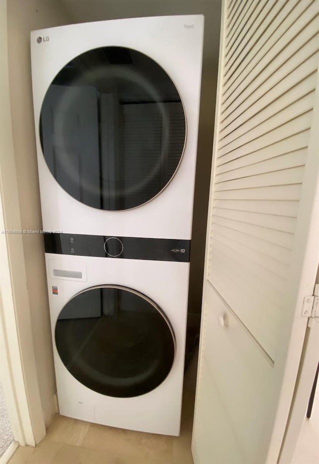 laundry room featuring stacked washer and dryer and light tile patterned flooring