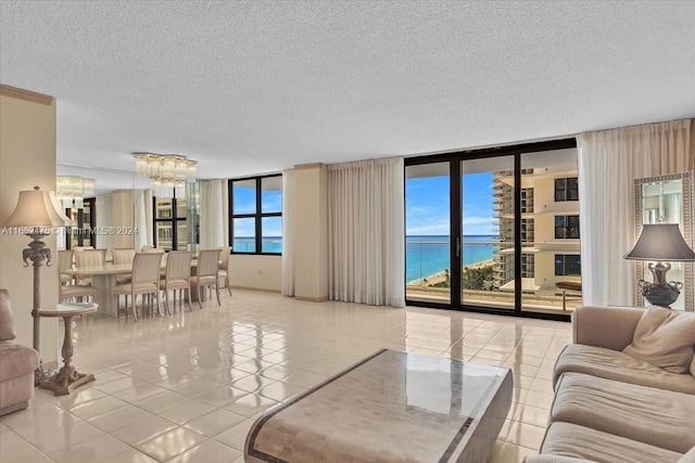 tiled living room with a water view, a textured ceiling, plenty of natural light, and expansive windows