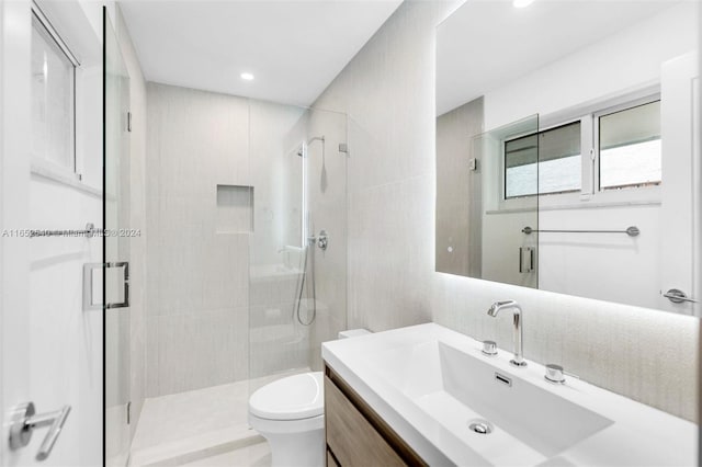 bathroom featuring a shower with door, vanity, and toilet