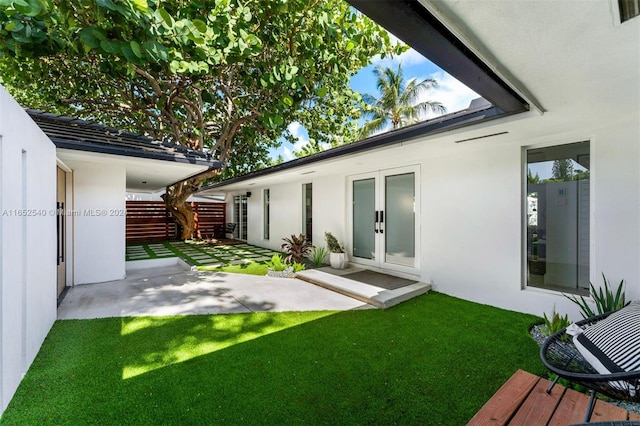 rear view of property featuring a patio area, a yard, and french doors