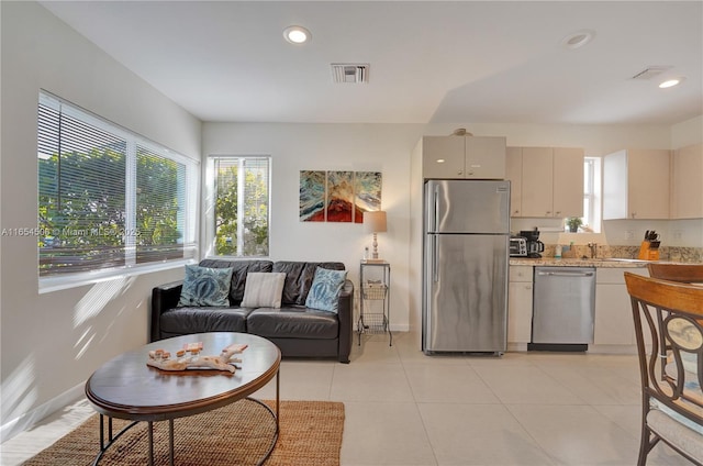 kitchen with stainless steel appliances, light tile patterned flooring, a wealth of natural light, and cream cabinetry