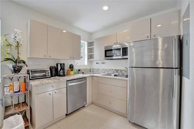 kitchen featuring light tile patterned flooring, sink, appliances with stainless steel finishes, light stone countertops, and cream cabinets