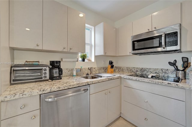 kitchen with sink, stainless steel appliances, cream cabinets, light stone countertops, and light tile patterned flooring