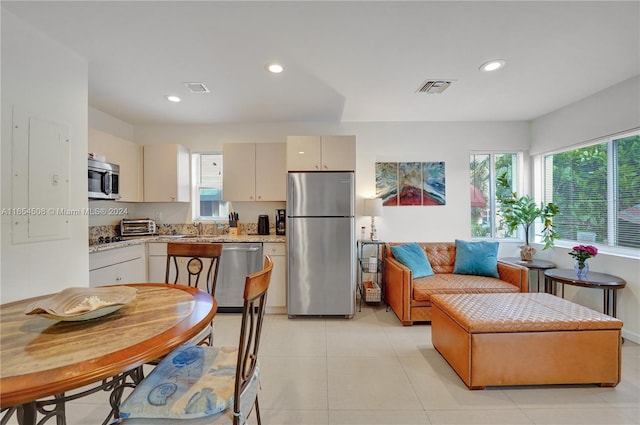 kitchen with sink, light tile patterned floors, stainless steel appliances, and cream cabinetry