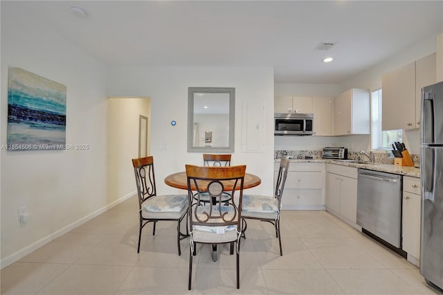 kitchen featuring stainless steel appliances, sink, light tile patterned floors, and light stone counters