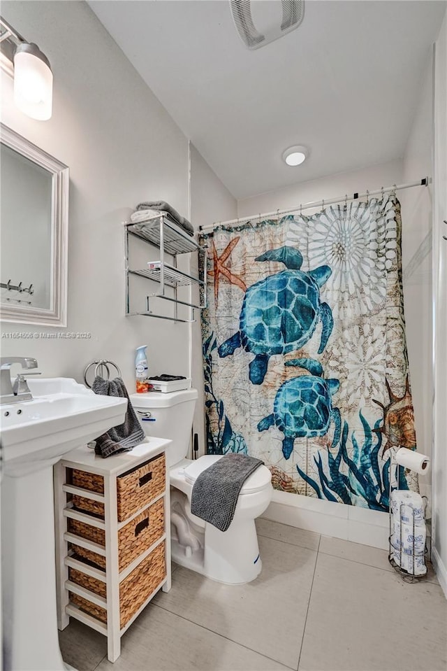 bathroom with shower / bathtub combination with curtain, tile patterned floors, and toilet