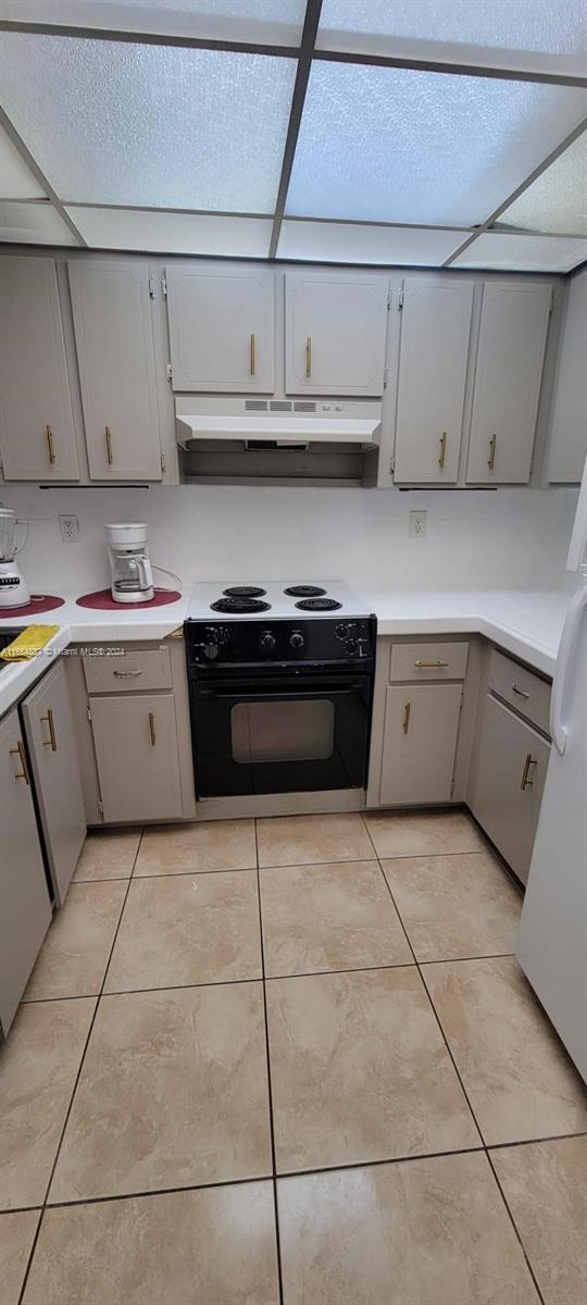 kitchen with light tile patterned floors, gray cabinets, and black range with electric cooktop