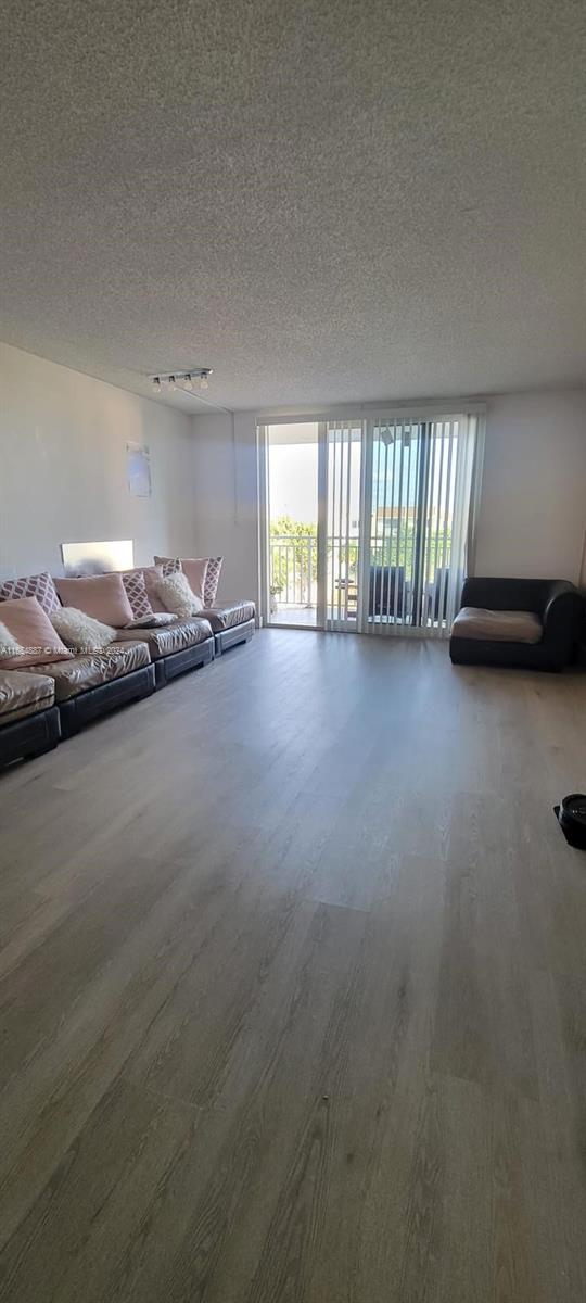 unfurnished living room featuring hardwood / wood-style flooring and a textured ceiling