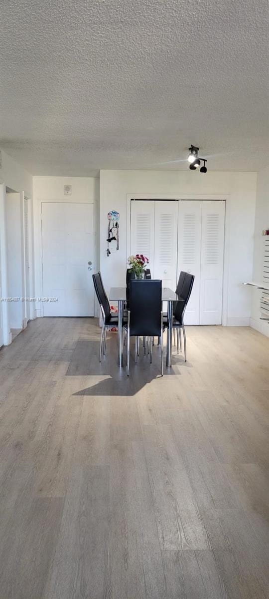 dining room featuring wood-type flooring and a textured ceiling