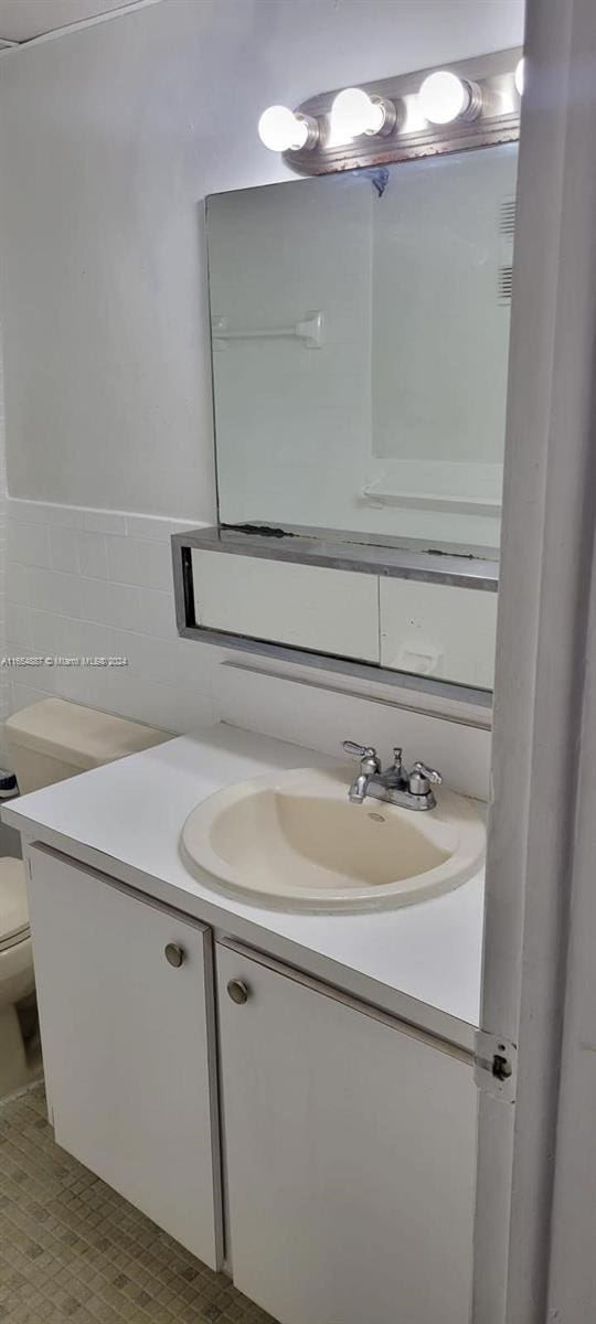 bathroom with vanity, tile walls, and toilet