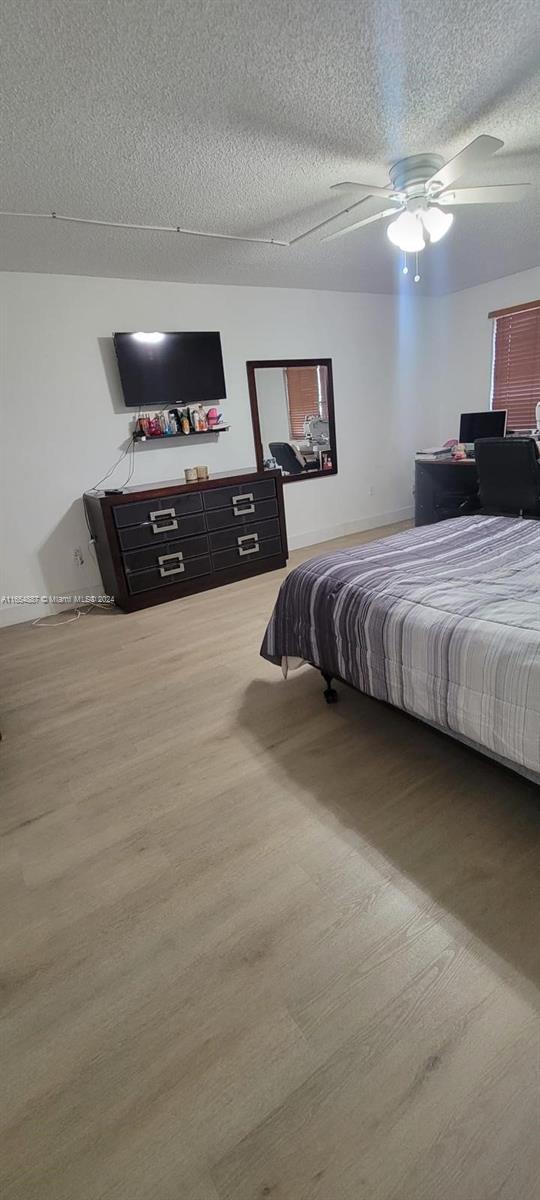 bedroom with wood-type flooring, a textured ceiling, and ceiling fan