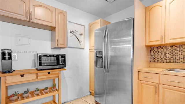 kitchen with light tile patterned floors, stainless steel fridge, decorative backsplash, and light brown cabinets