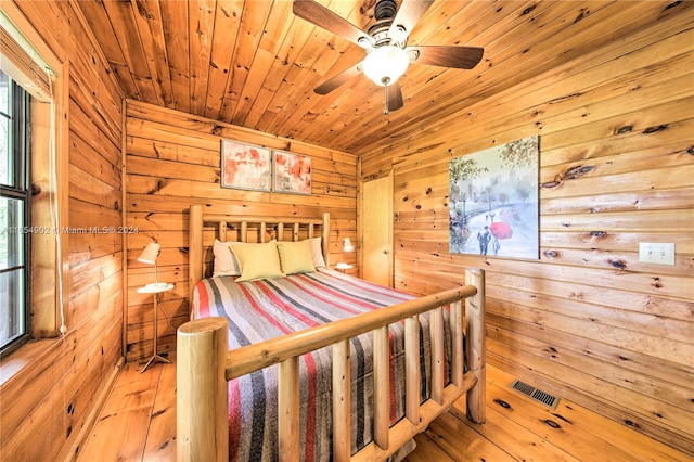 bedroom featuring ceiling fan, wood ceiling, wood walls, and light hardwood / wood-style floors