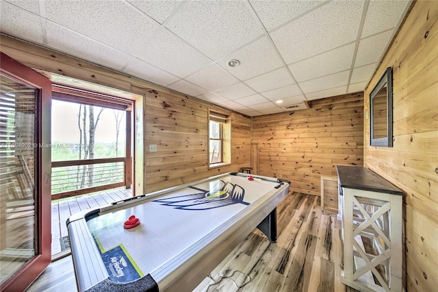 playroom with a drop ceiling, wood walls, and hardwood / wood-style floors