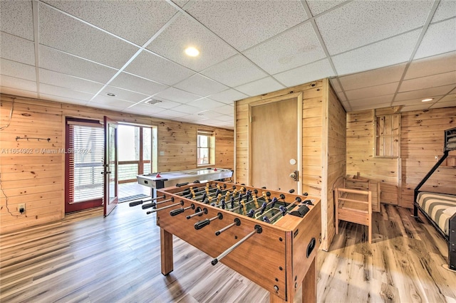 game room with a drop ceiling, wooden walls, and hardwood / wood-style flooring