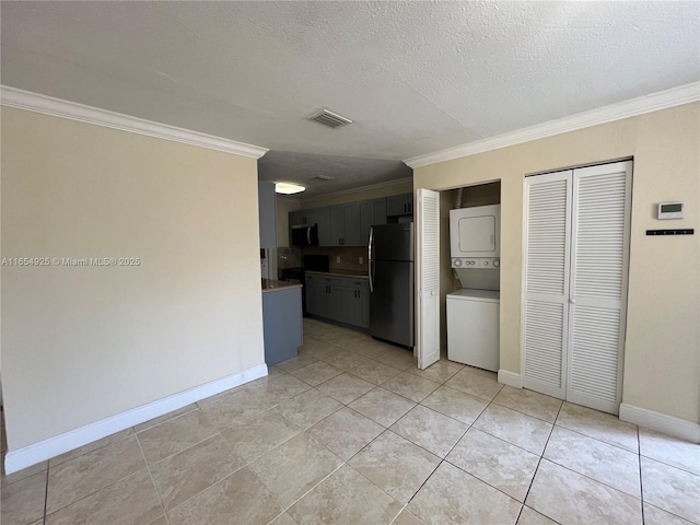 kitchen with stainless steel fridge, a textured ceiling, stacked washer / drying machine, light tile patterned floors, and ornamental molding