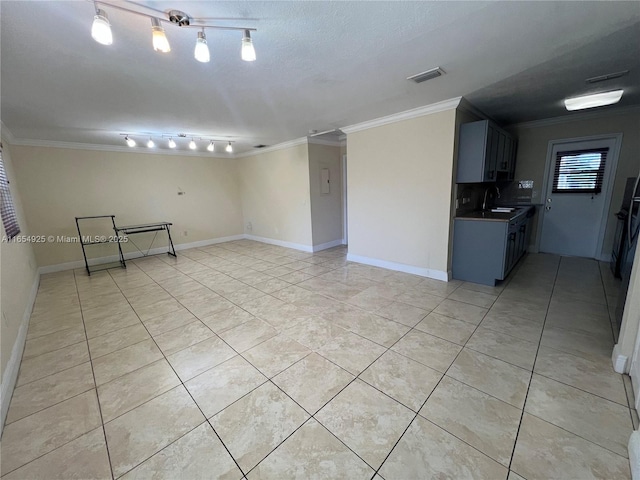 empty room with light tile patterned floors, a textured ceiling, crown molding, and sink