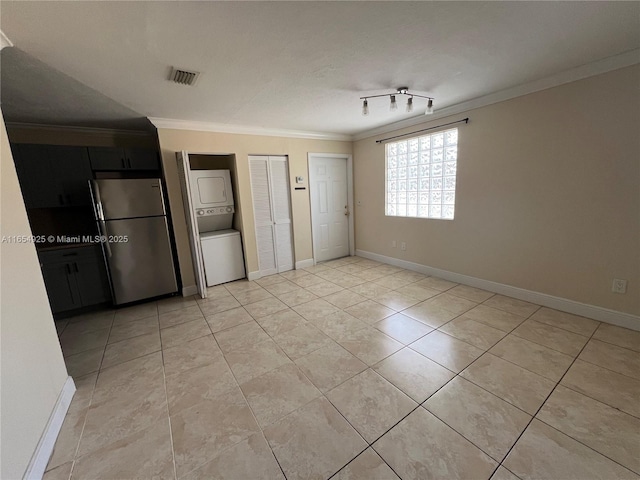 unfurnished bedroom with stainless steel fridge, stacked washer and dryer, light tile patterned floors, two closets, and ornamental molding