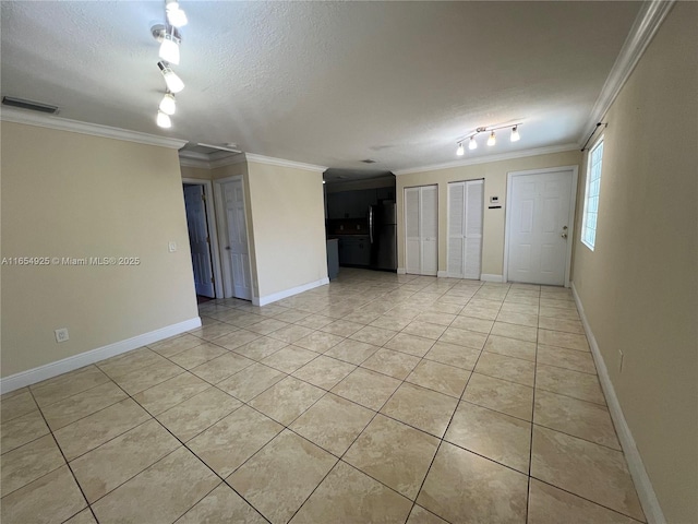 tiled spare room featuring a textured ceiling and crown molding